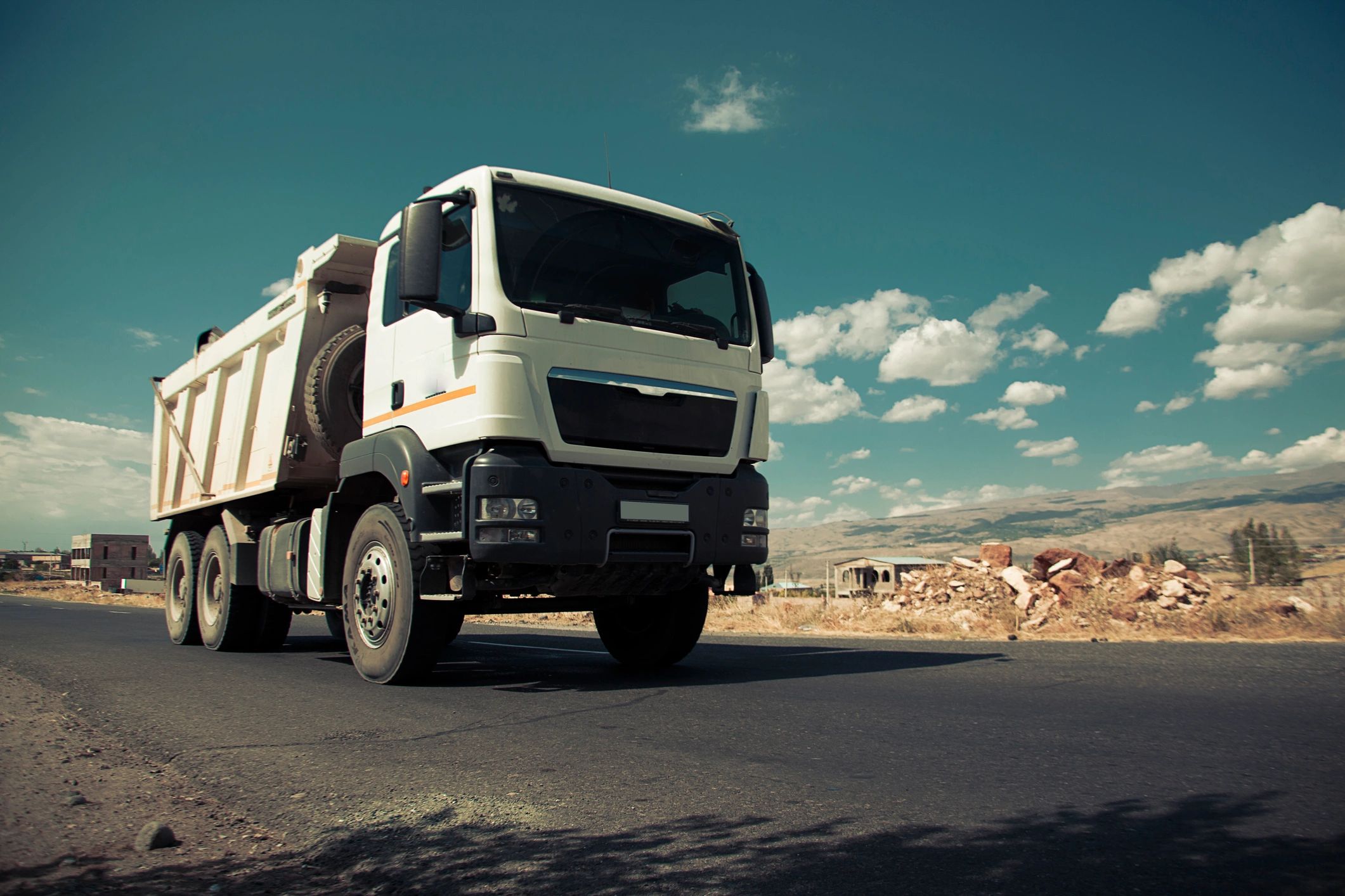 Work truck driving on a road under a blue sky